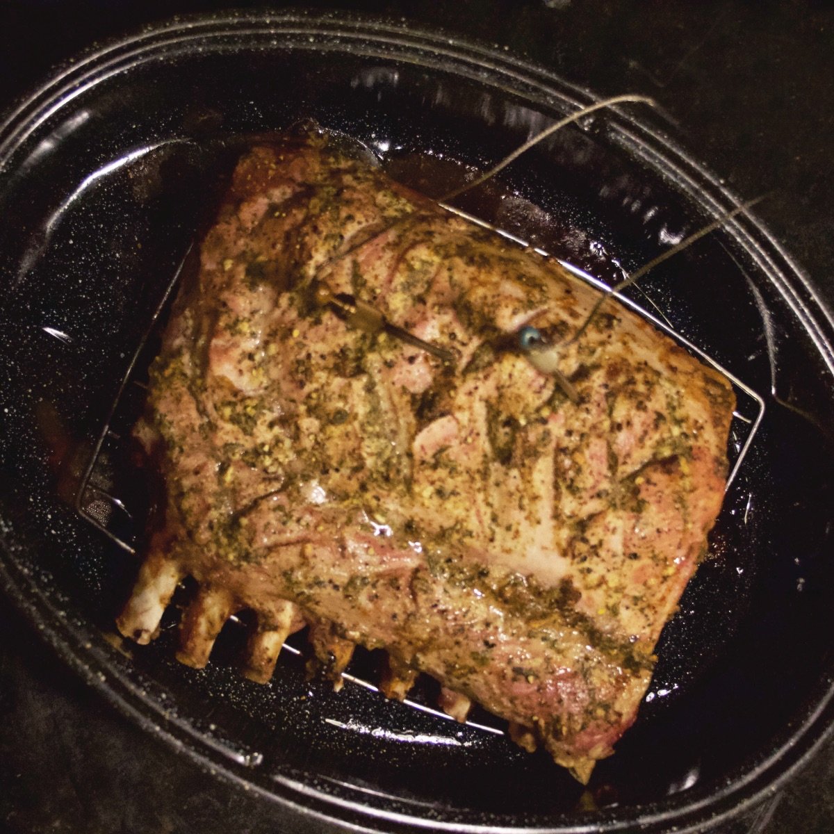 Overhead view of fully cooked rack of pork still in roasting pan just pulled out of the oven