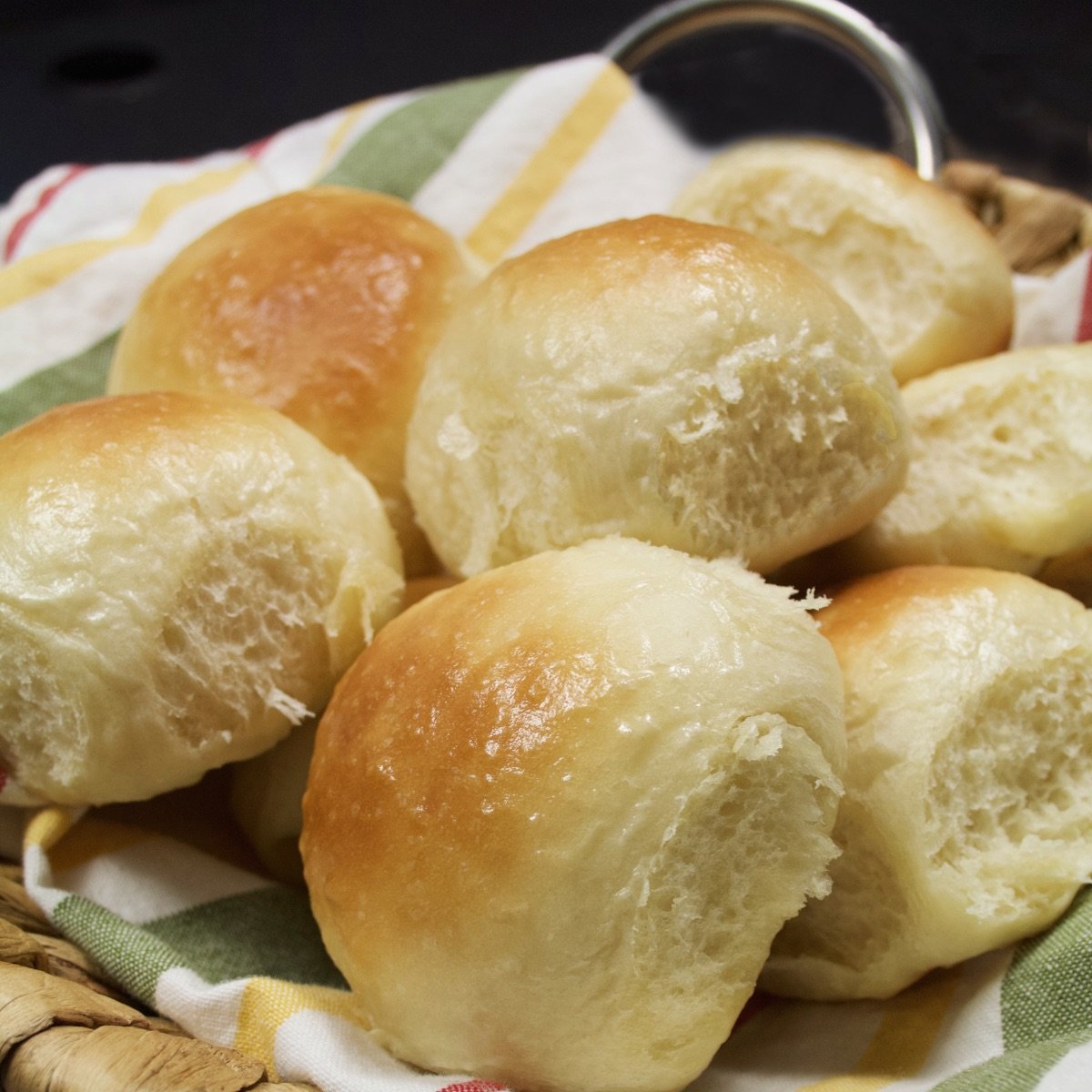 Close up side view of seven freshly made dinner rolls in a basket.