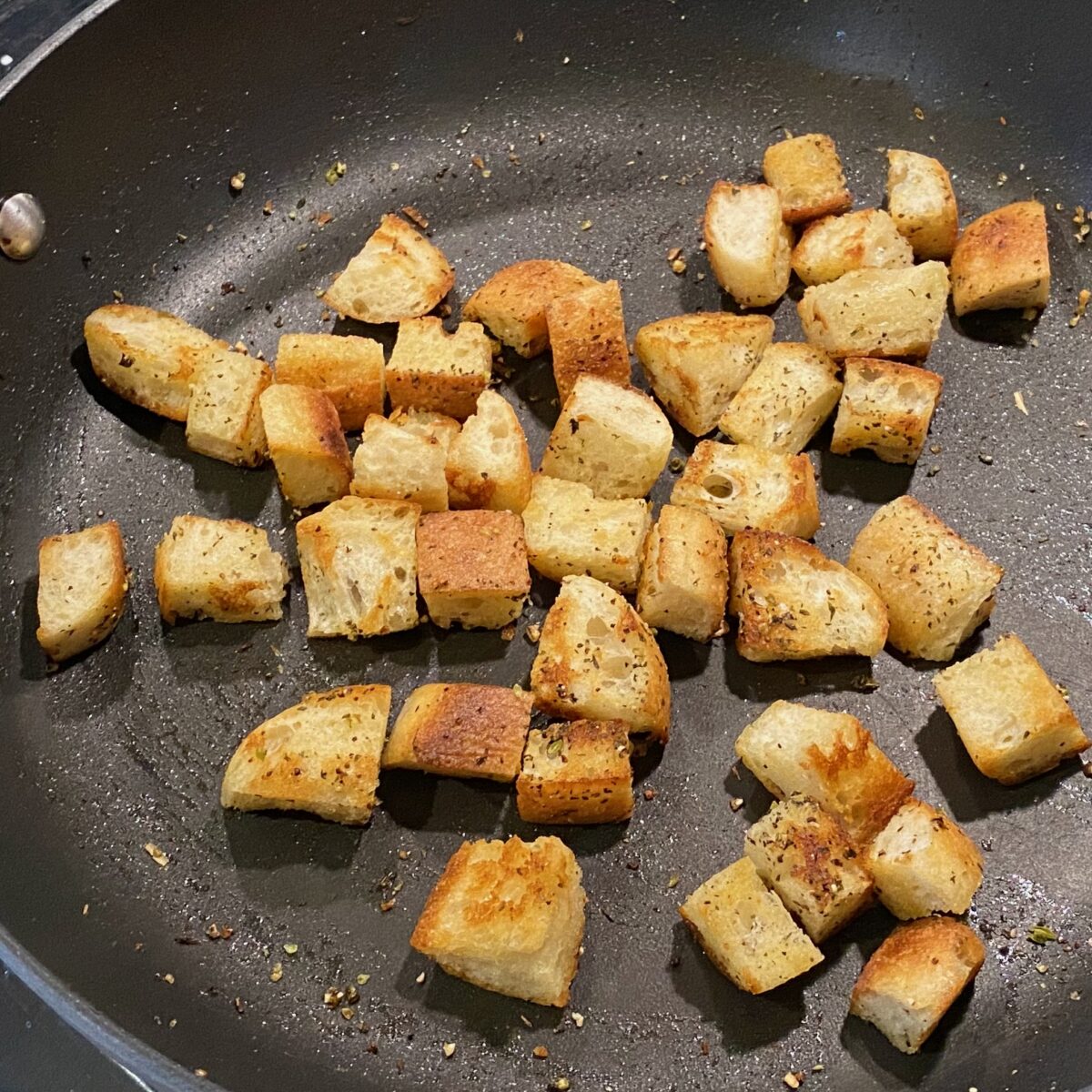Freshly made stovetop croutons that have just been seasoned and are still in the skillet.
