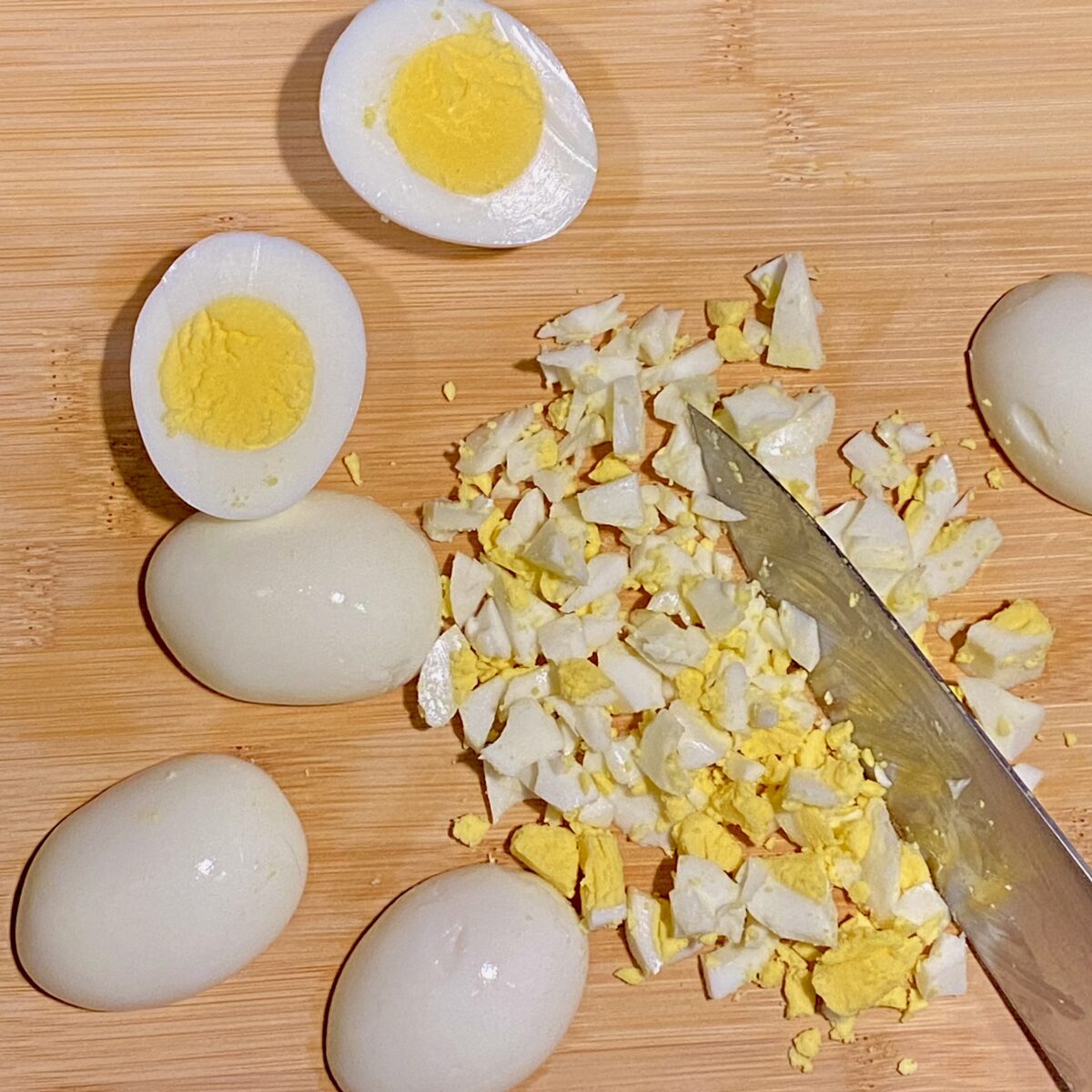 Hard boiled eggs on a cutting board: some have been chopped, others are only halved. The yolks are perfectly cooked, and the whites are tender and not rubbery.