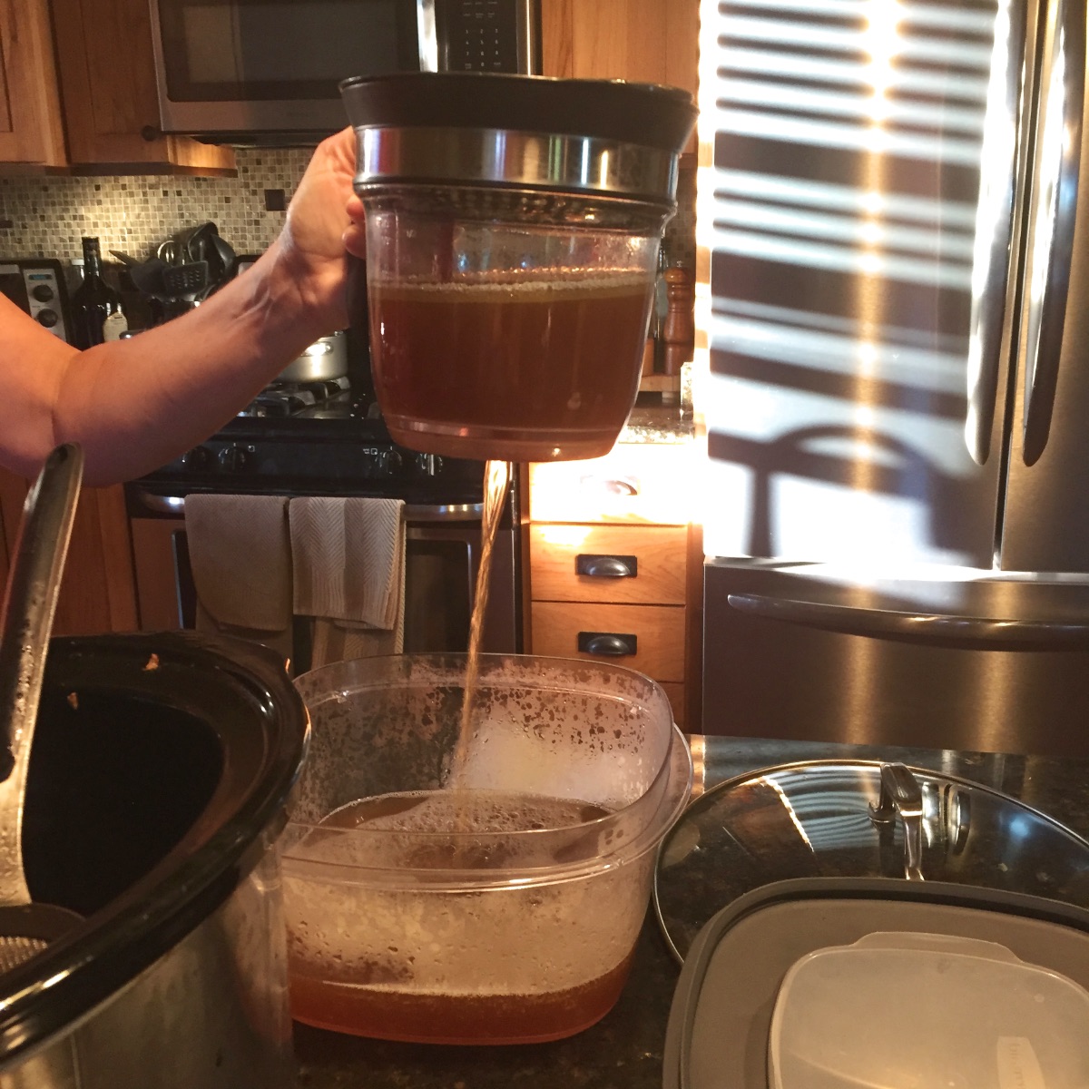 Degreasing the duck pho broth. You can see the fat: it's a very thin, light layer at the top of the liquid in the fat separator. The broth drains from the bottom of the fat separator into a storage container.