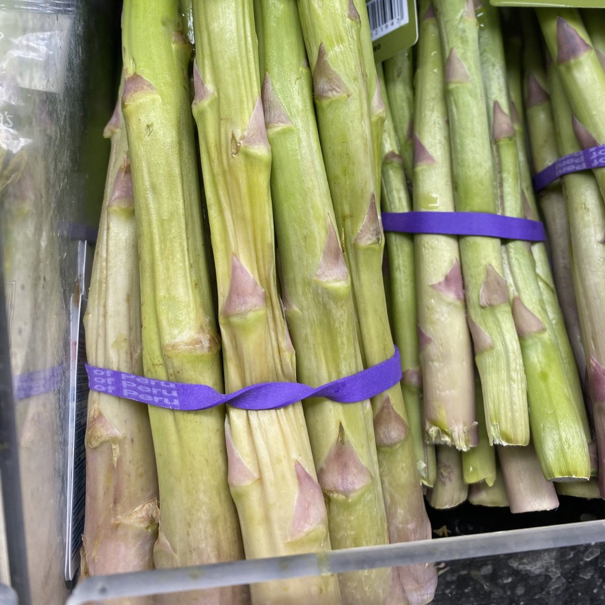 Bunches of asparagus in our local produce department. The bunch on the left is super wilty and wrinkly, so I'd never buy that one. The bunch next to it is a much better choice.