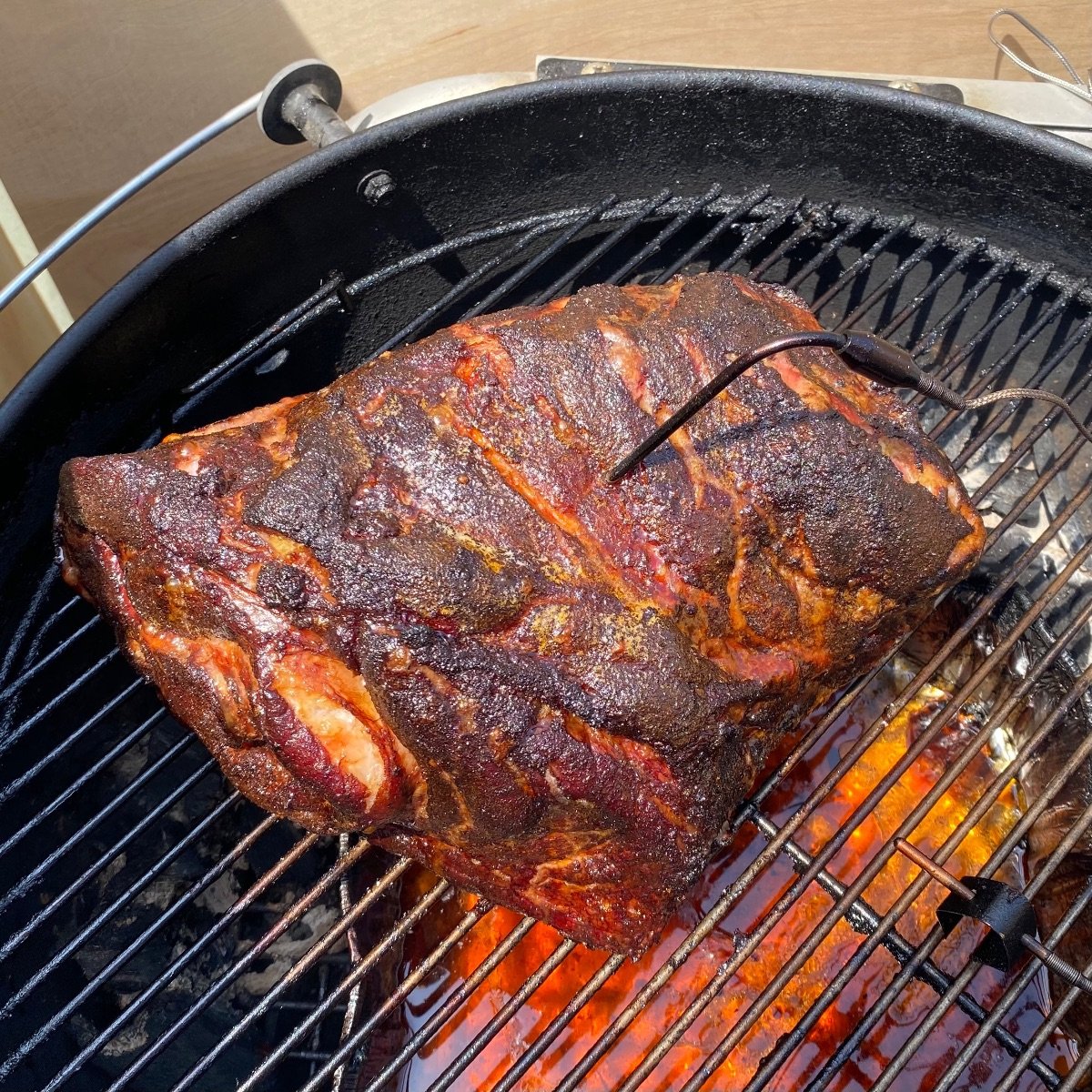 Top view of smoked pork butt on charcoal grill after smoking 5.5 hours.