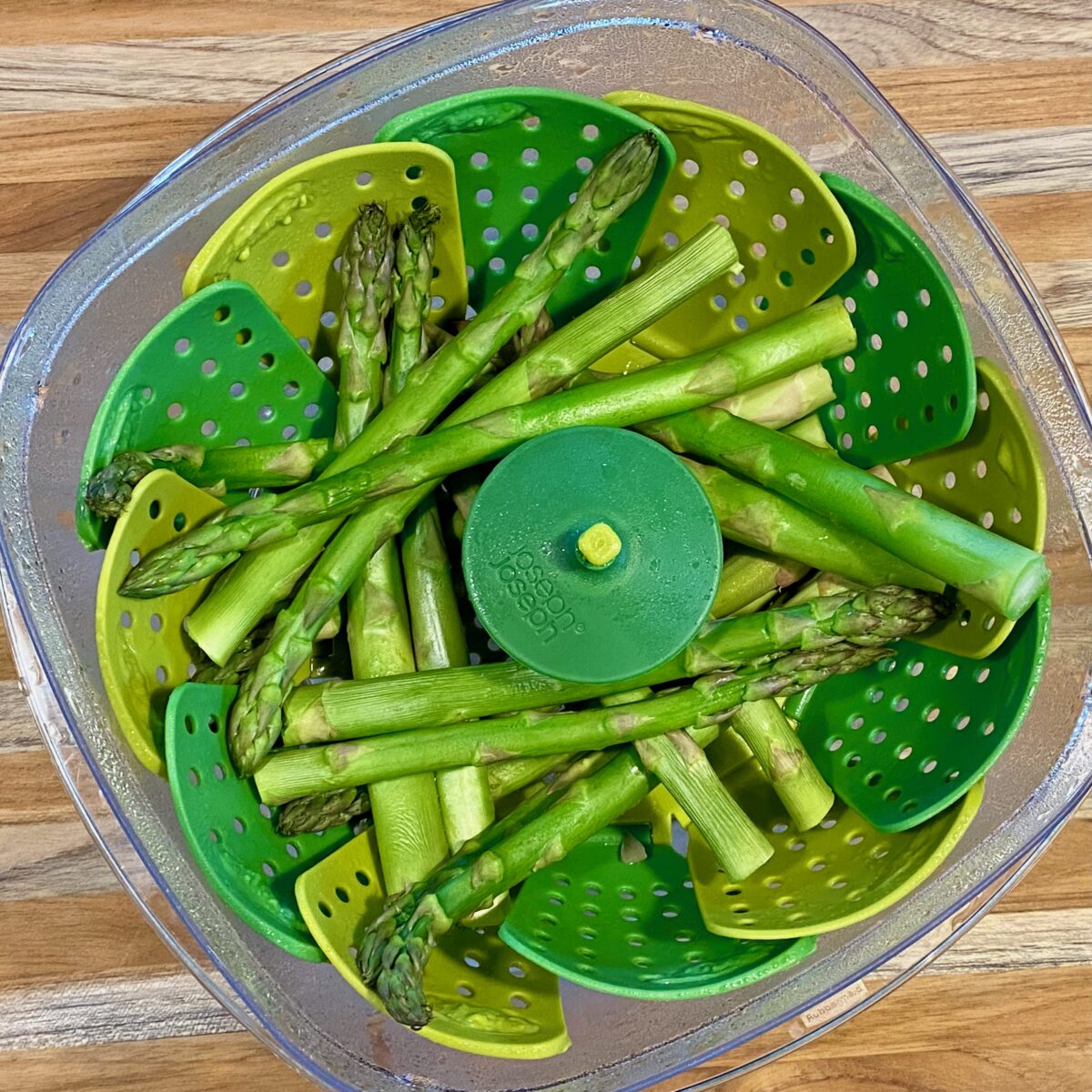 Top view of freshly microwaved asparagus still inside a vegetable steamer.