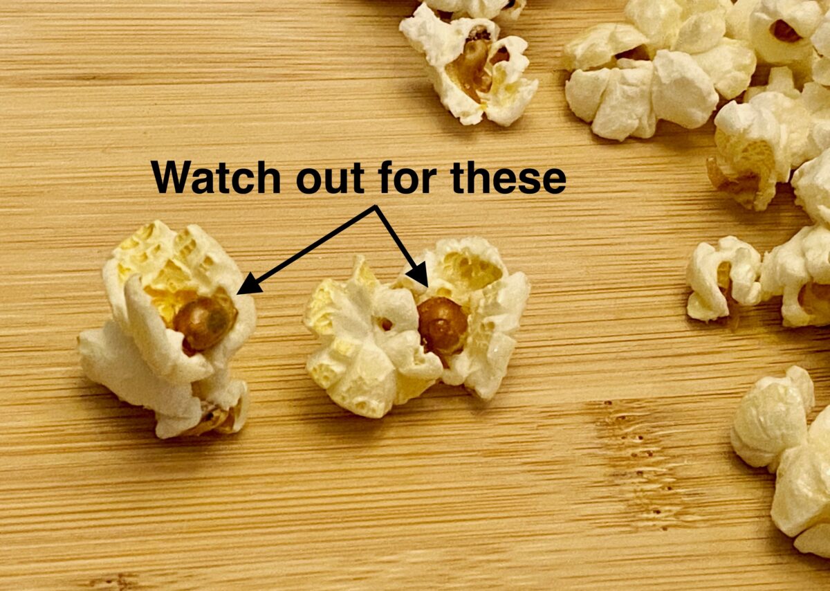Close up view with two pieces of kettle corn with unpopped kernels stuck to them.