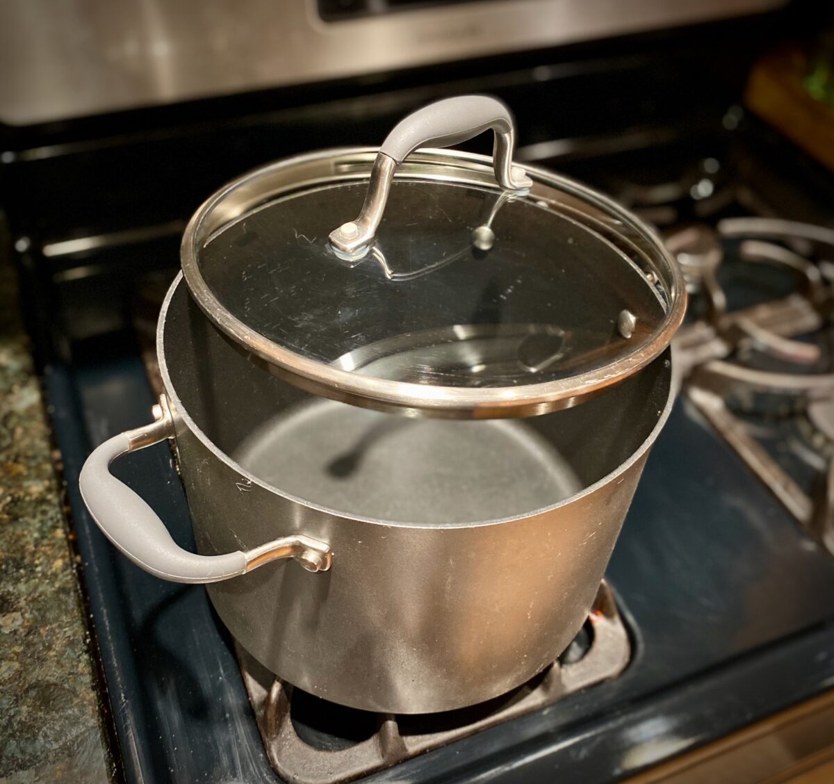 An empty large pan that has a lid to one side which is used to make kettle corn.