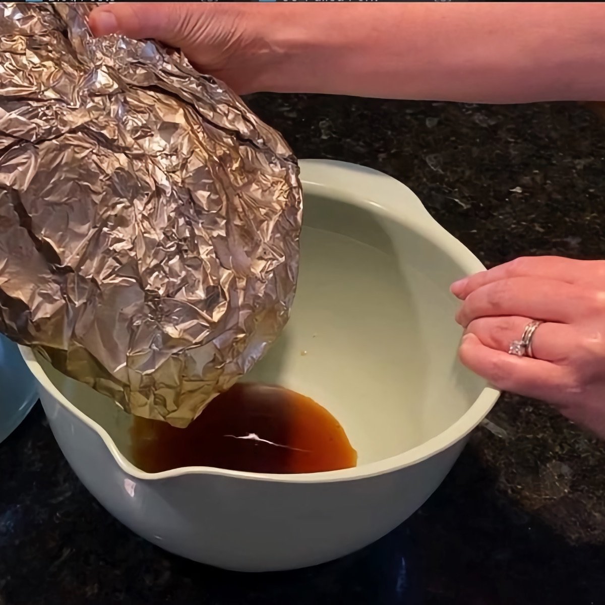 Pouring juices from the pork butt wrap to degrease and serve with the pulled pork.