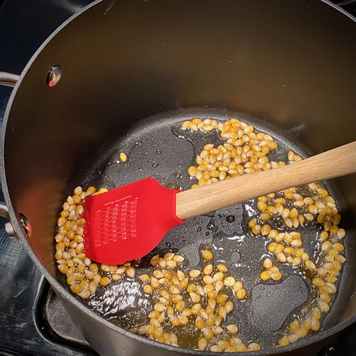 Top view of popcorn, sugar and oil  sizzling in a hot pan.