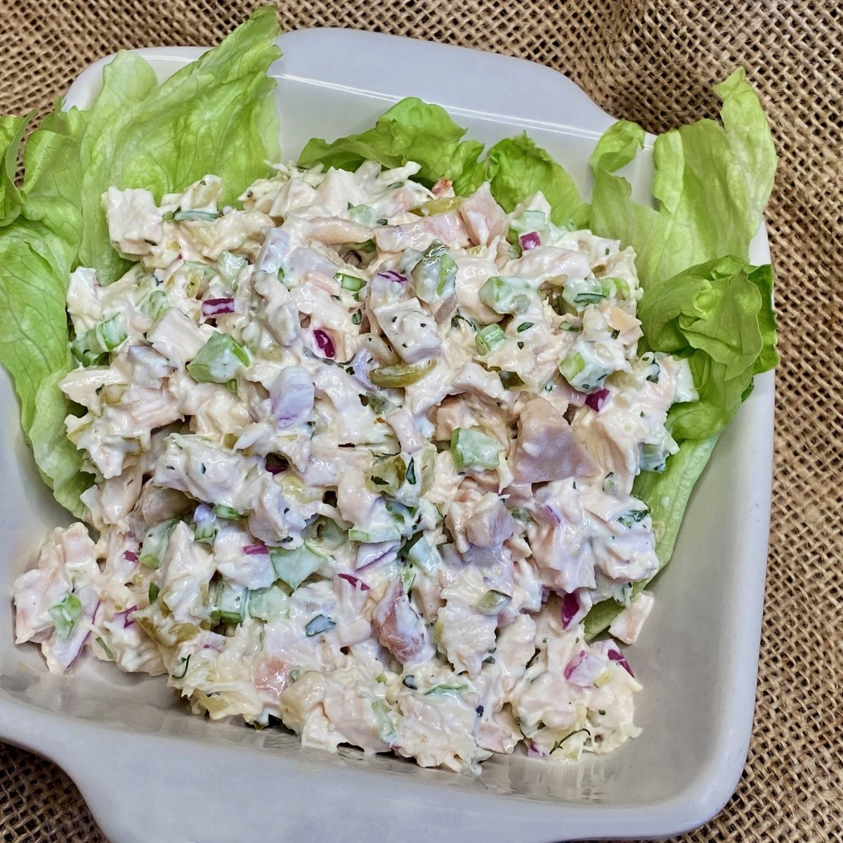 Chicken Salad with Relish on a bed of lettuce in a white dish.