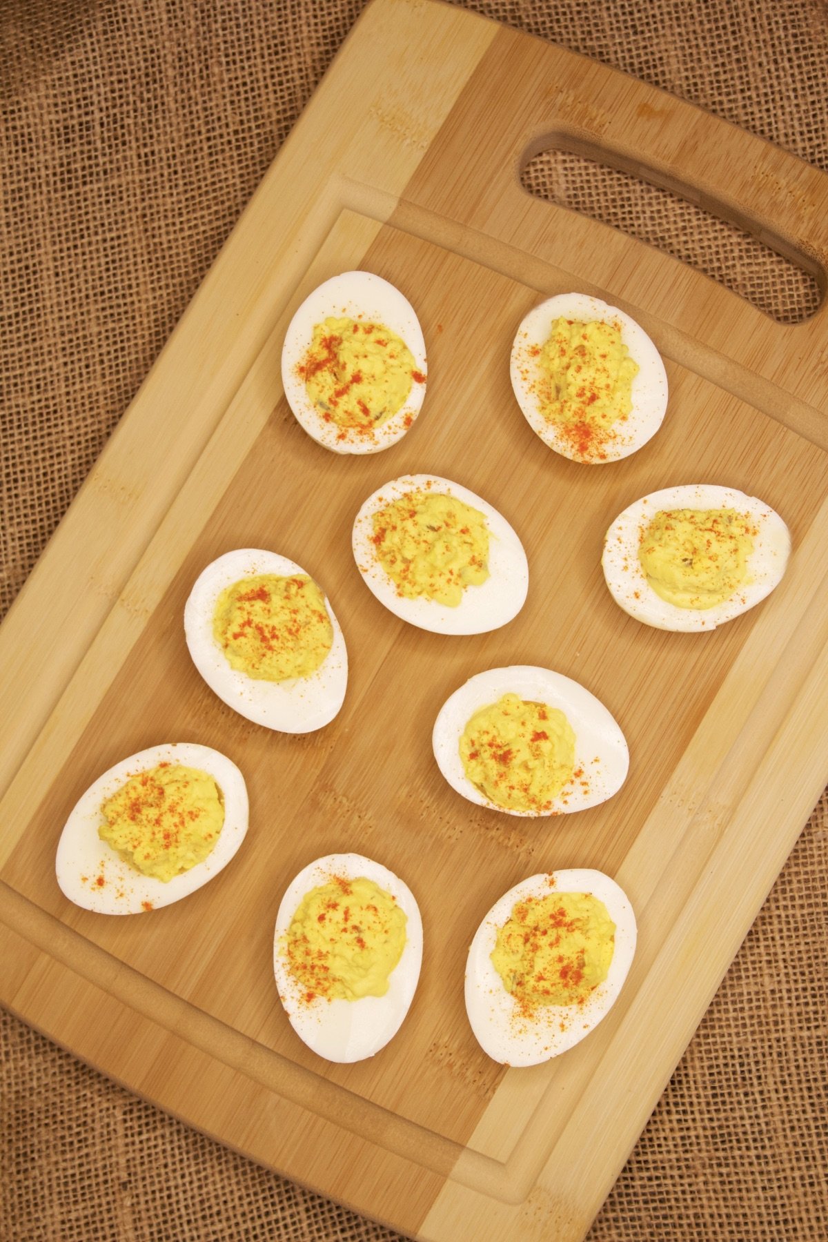 Deviled Eggs with Relish, sprinkled with paprika, sitting atop a wooden cutting board.