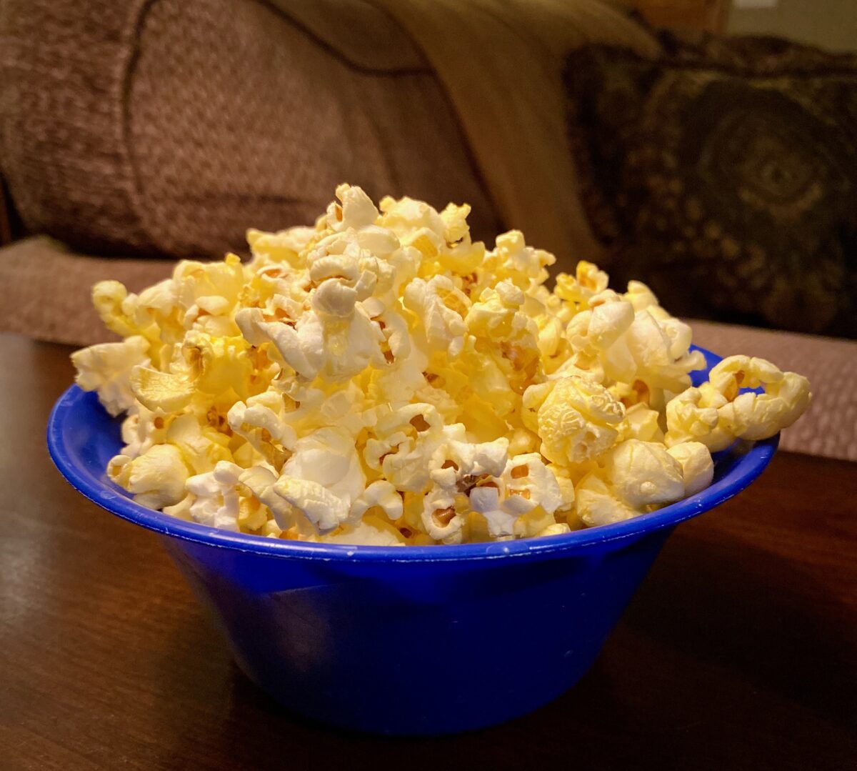 A blue bowl full of movie theater popcorn.