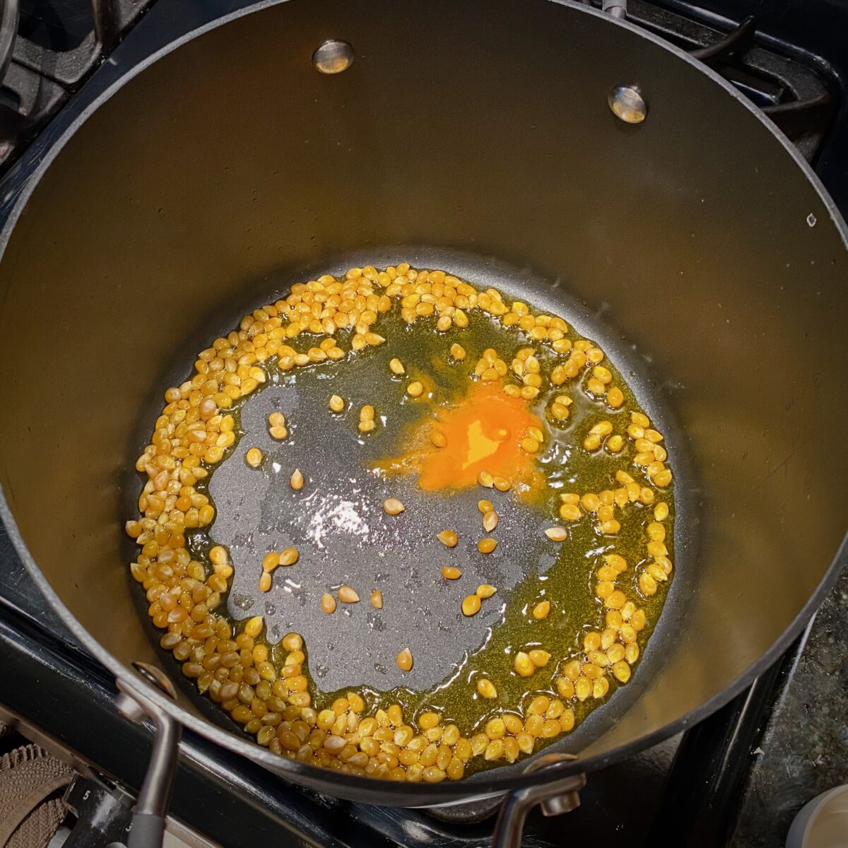 Top view of popcorn, Flavacol salt and oil sizzling in a hot pan.
