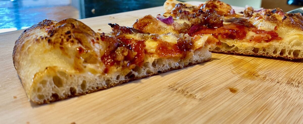 Side view of two pizza slices on a cutting board.