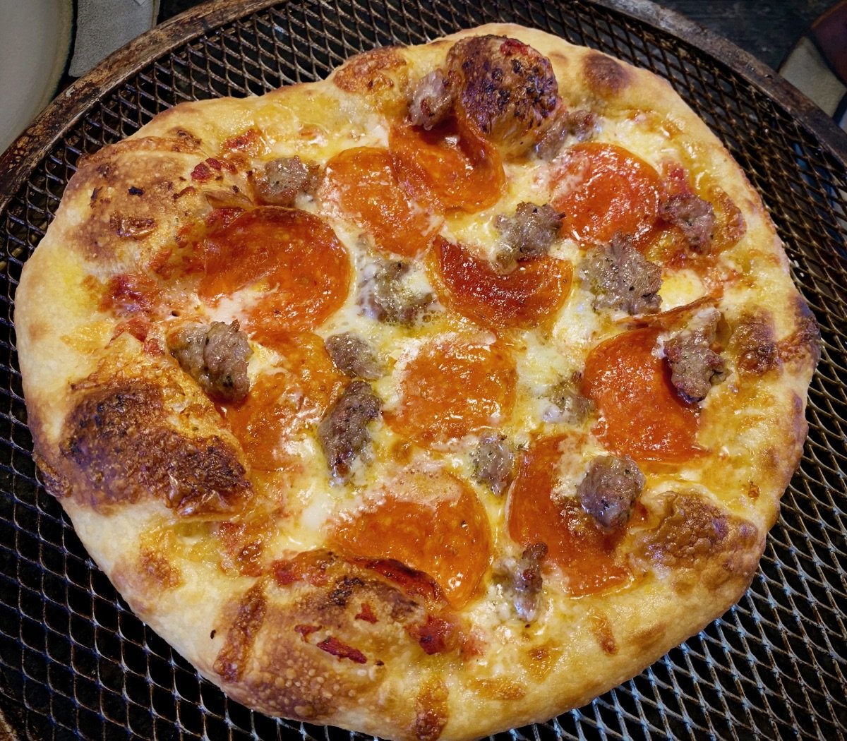 Top view of a freshly baked sausage and pepperoni pizza made with cold fermented pizza dough.