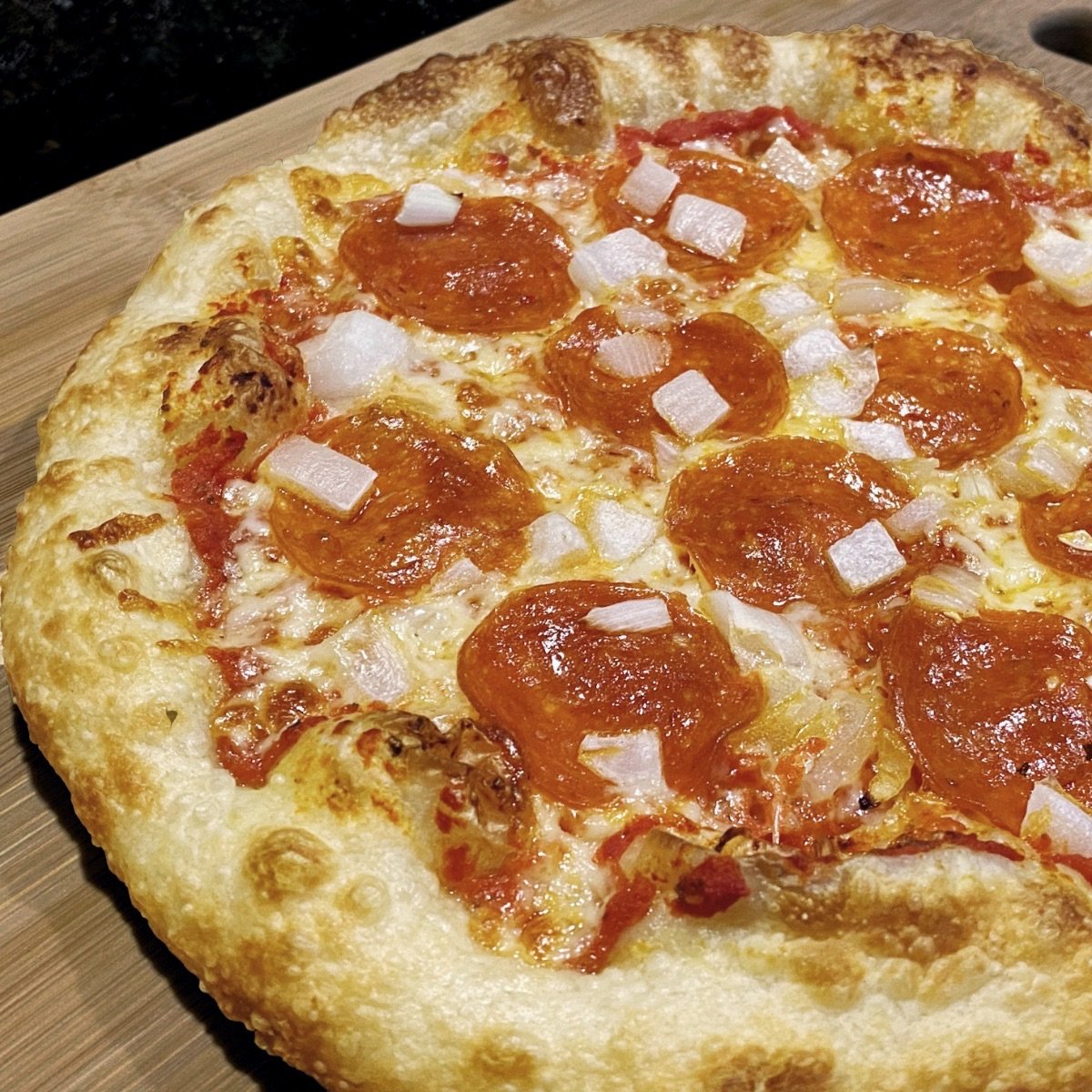 Close up view of a freshly baked pizza that details the bubbly crust made from cold fermented pizza dough.