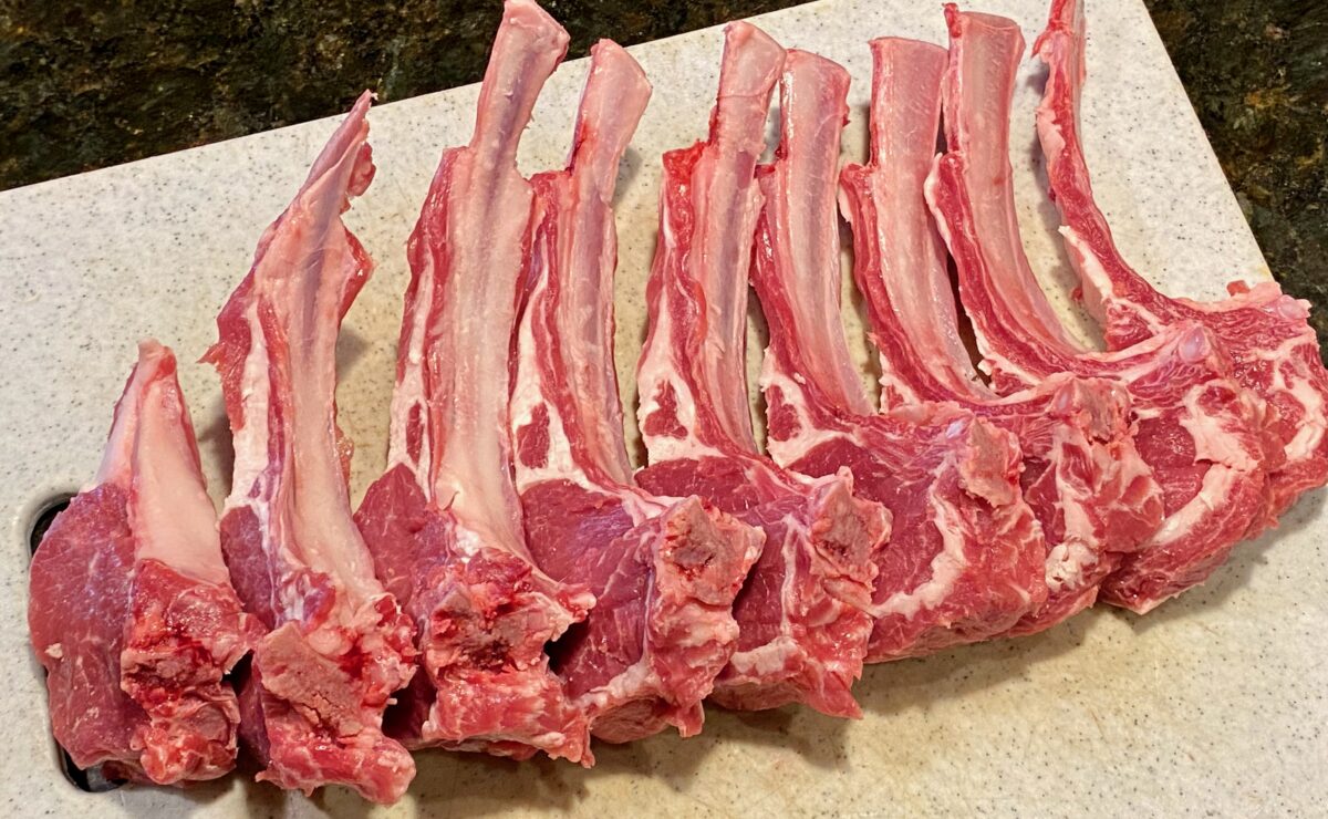 Top view of 9 lamb chops laying on a gray cutting board.
