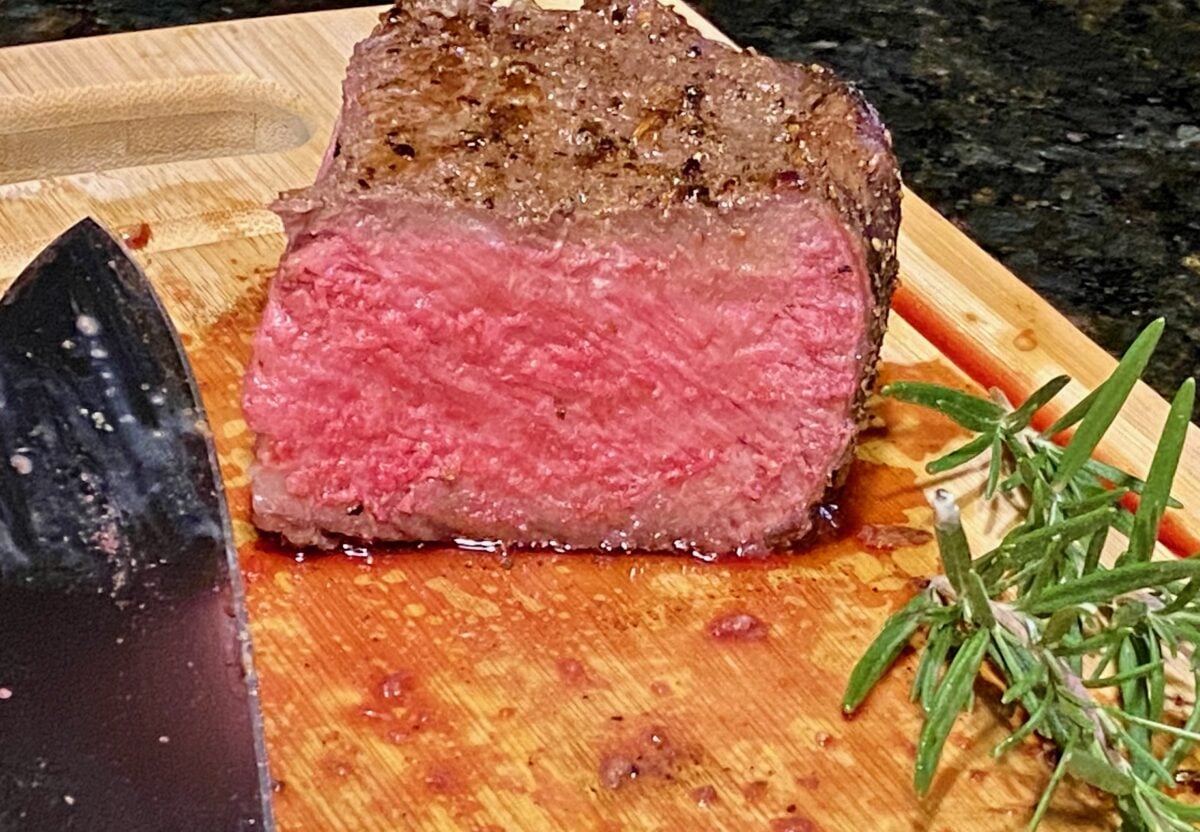 Close up view of a slice of reverse seared ribeye with a perfect medium rare doneness from top to bottom and end to end.