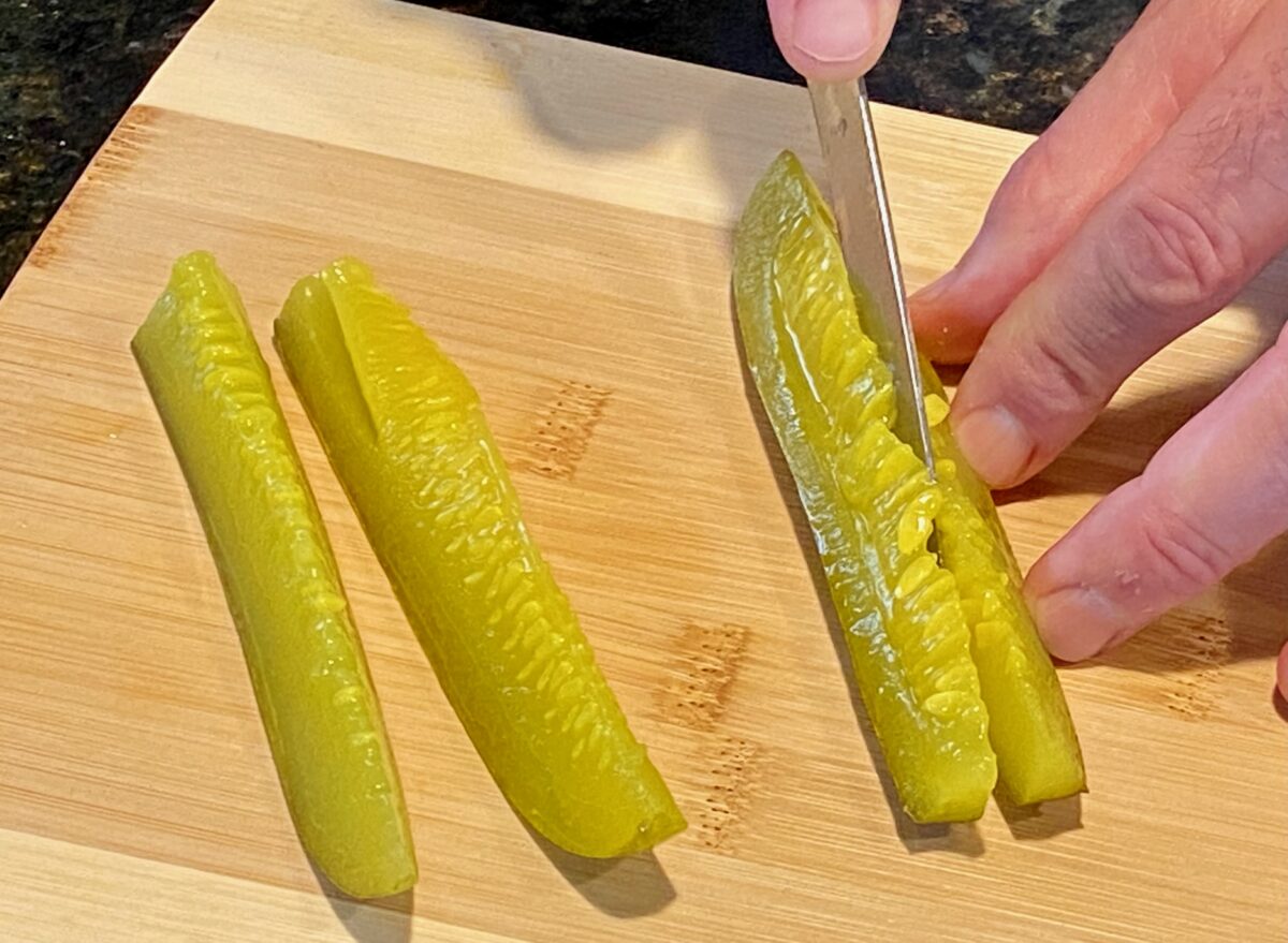 Slicing pickle spears in half lengthwise.