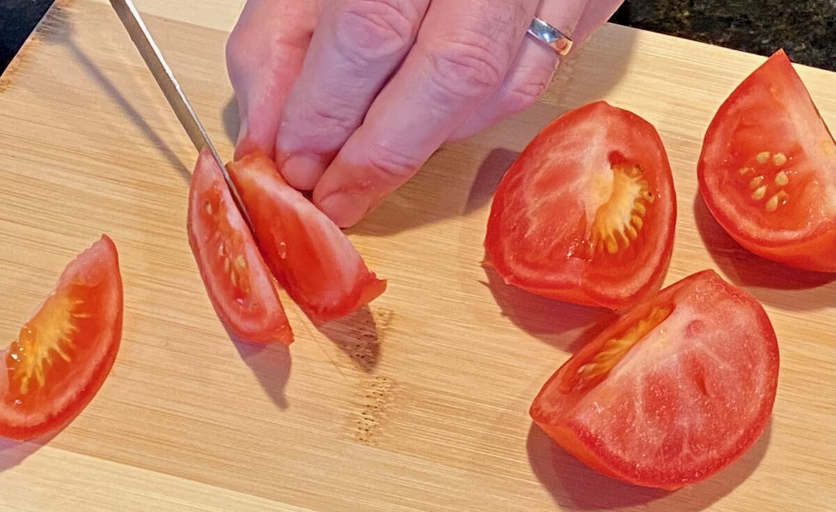 Slicing tomatoes into thin wedges.