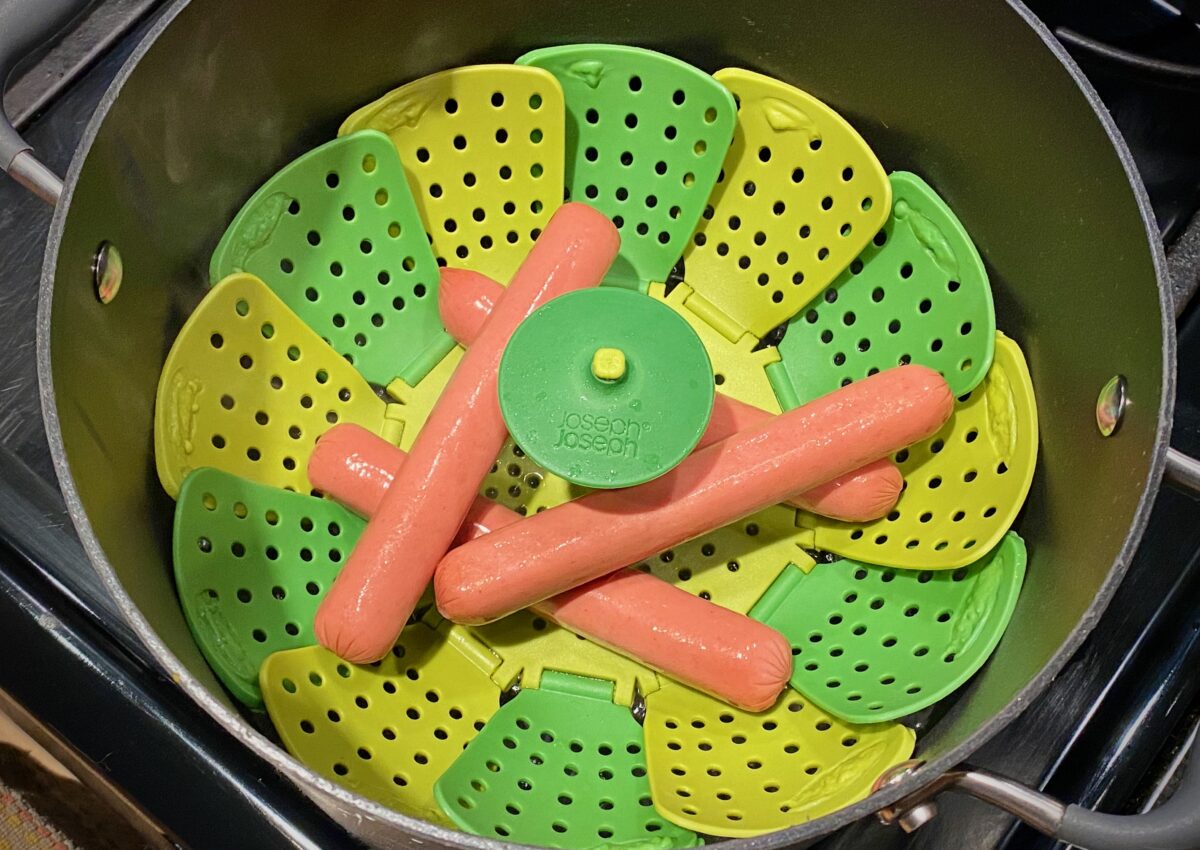 Steaming the all-beef franks in a pot with a steamer basket.