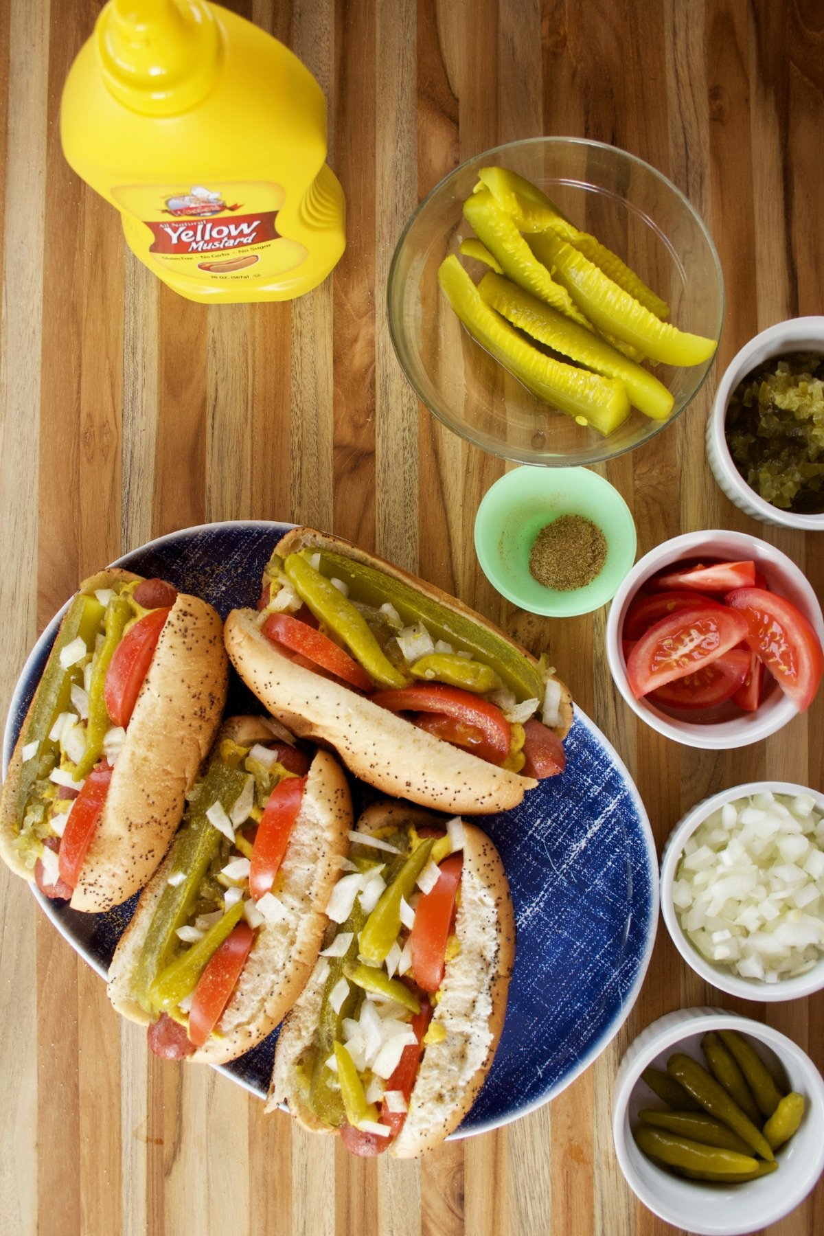 Assembled Chicago Hot Dogs on a blue platter next to all the fixings.