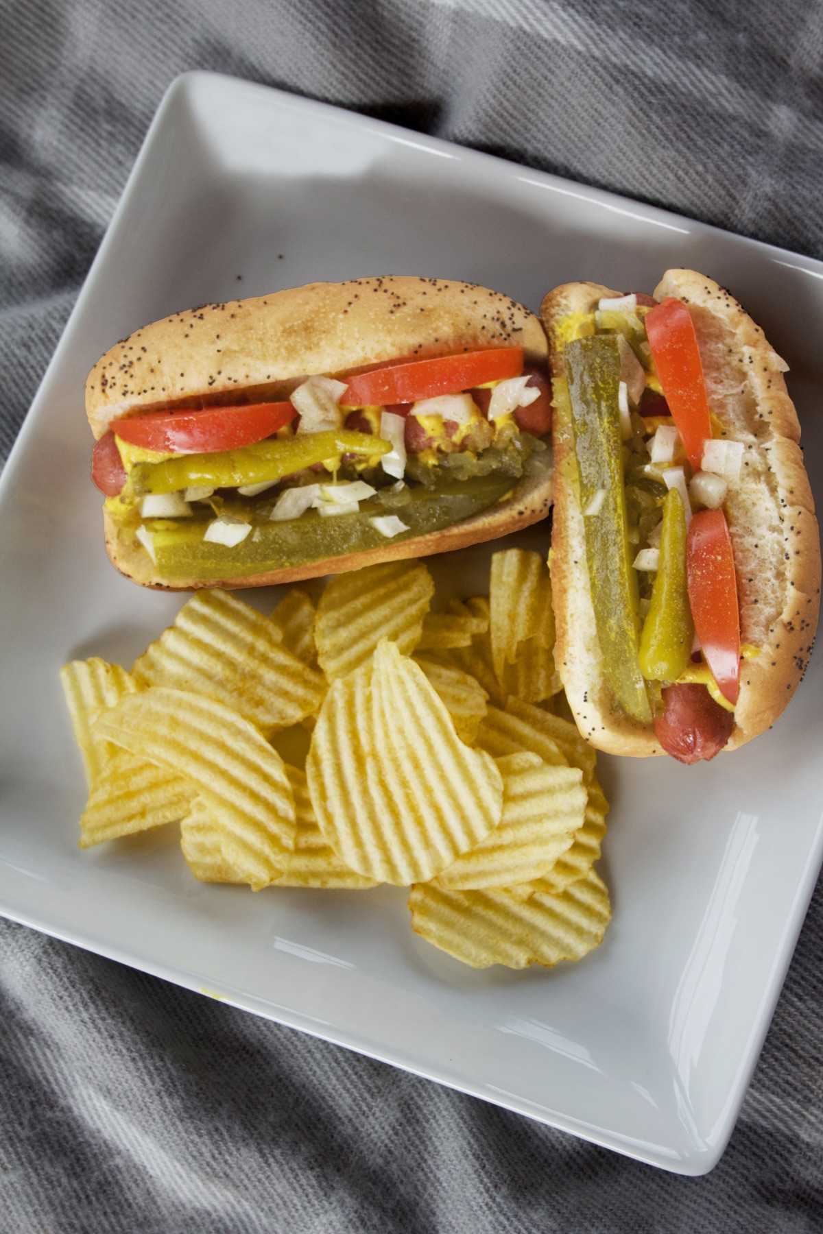 Chicago Dogs on a white plate with a serving of wavy potato chips.