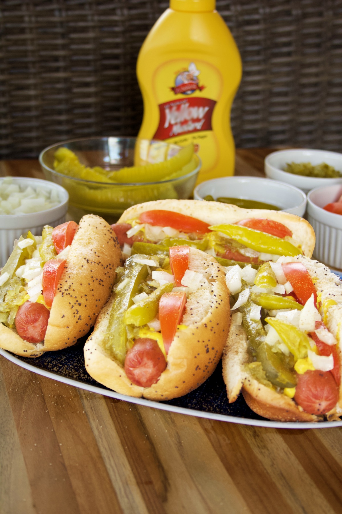 Closeup of a platter of Chicago Dogs in front of the lineup of toppings.