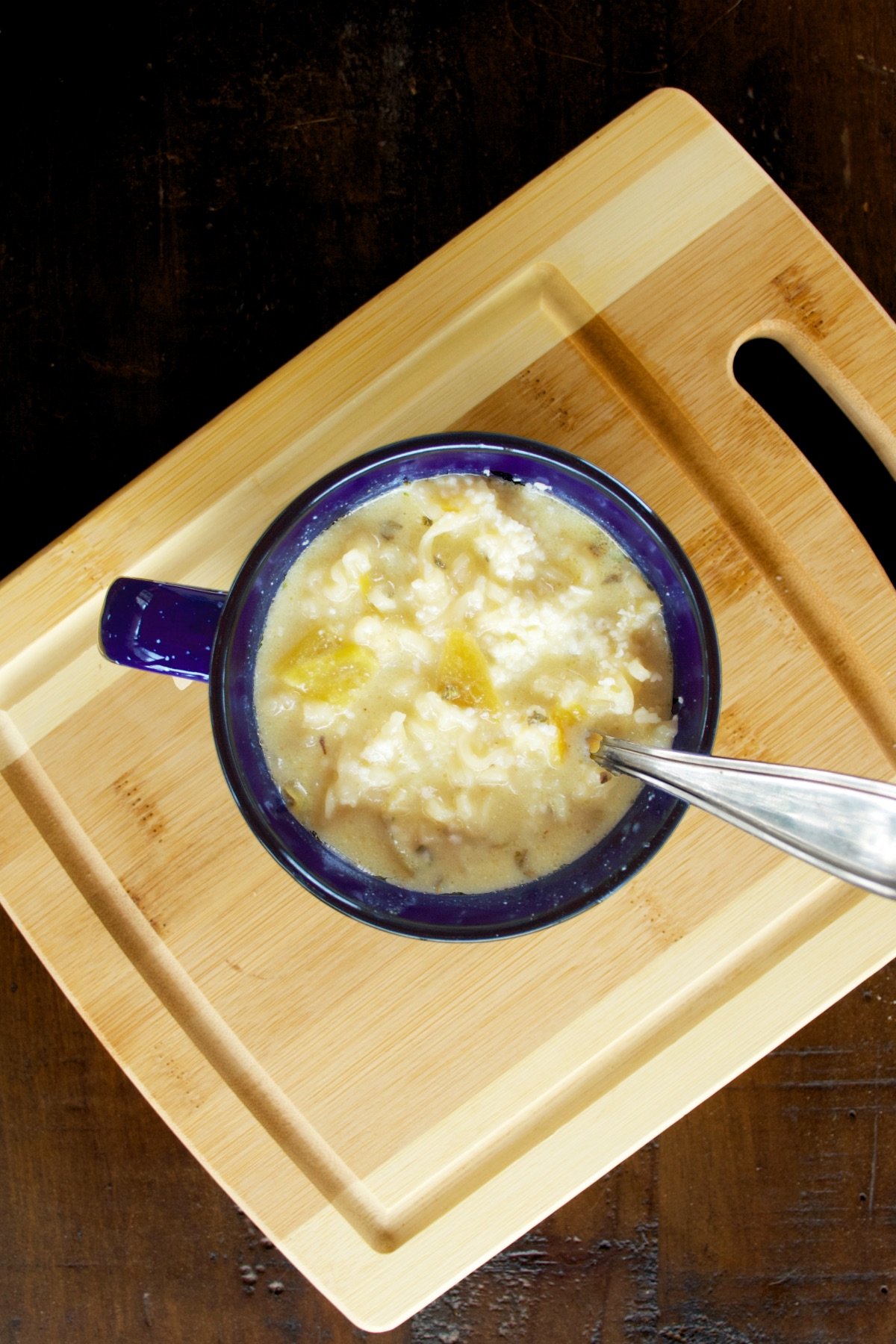 A mug full of steaming-hot green chile ramen soup, ready to eat.