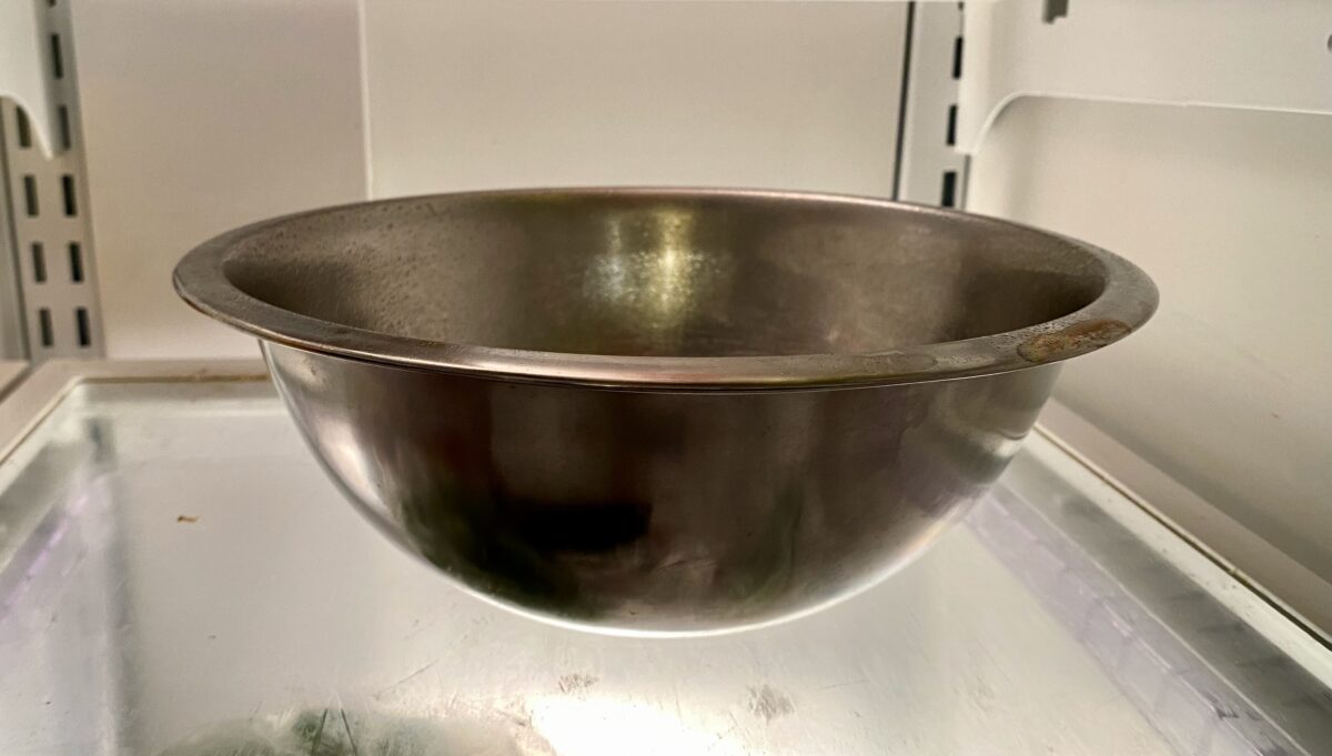 The mixing bowl with the pizza dough placed uncovered into the refrigerator for cooling.