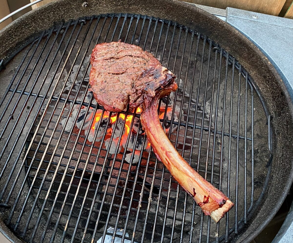 Steak positioned over red hot charcoals.