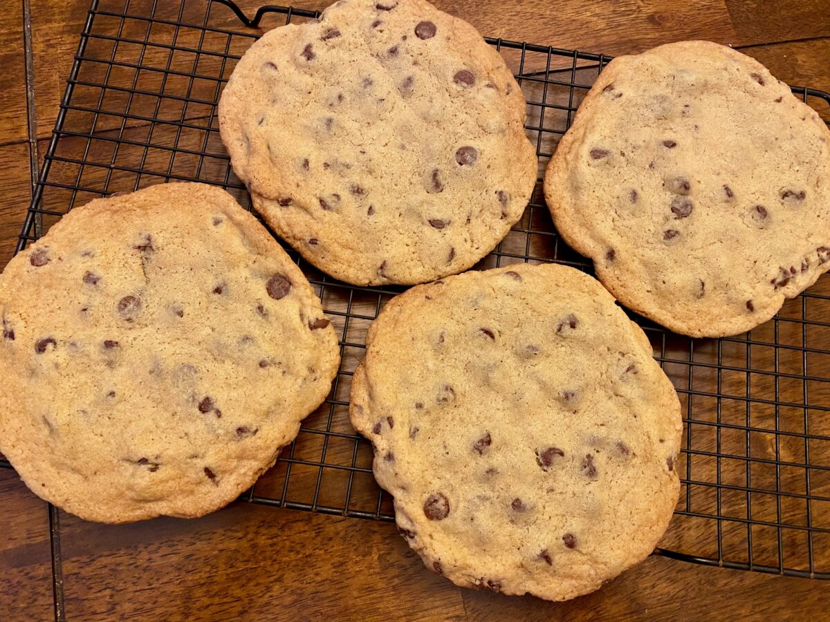 Monster chocolate chip cookies cooling on a wire rack after 10 minutes of cooling on the baking sheet.