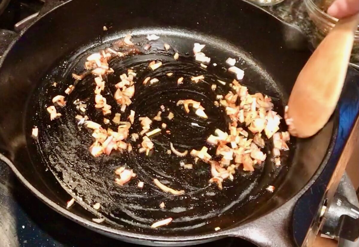 Shallots sauteed in a cast iron skillet.