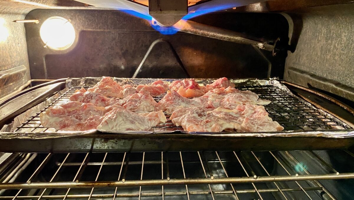 The baking sheet with yogurt-coated chicken thighs, placed in the oven under the broiler, set to high.