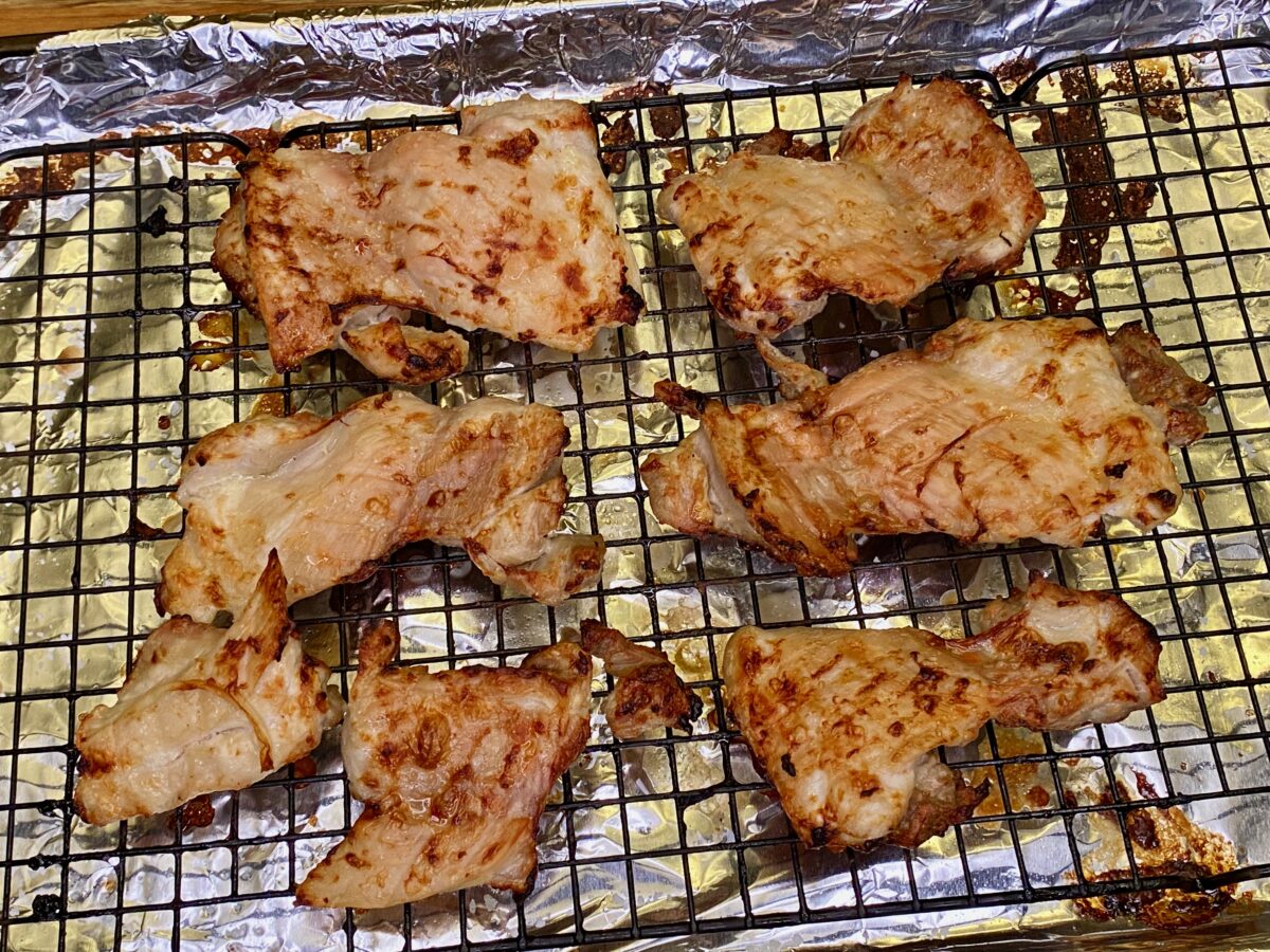 The lightly charred chicken thighs, removed from the oven after broiling, resting at room temperature.