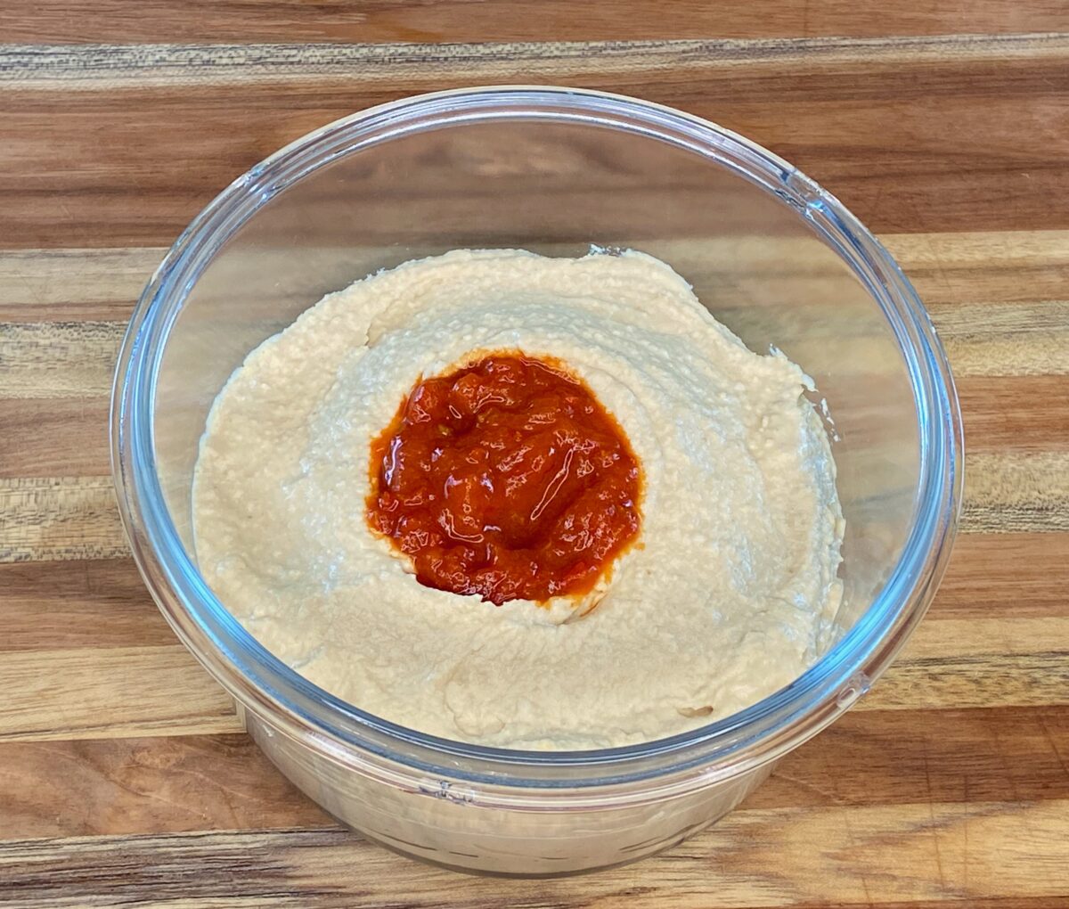 The hummus is now topped with the harissa and ready to serve.