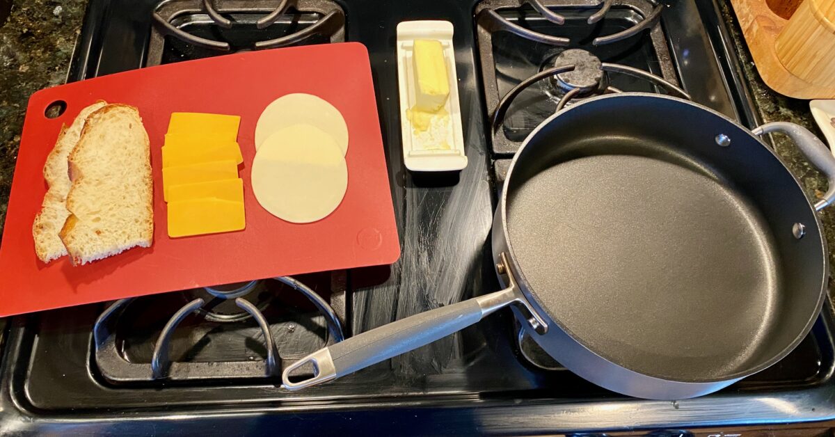 My set-up for making grilled cheese. I have the butter dish and a cutting board with my sliced bread and cheeses right next to my pre-heating pan.