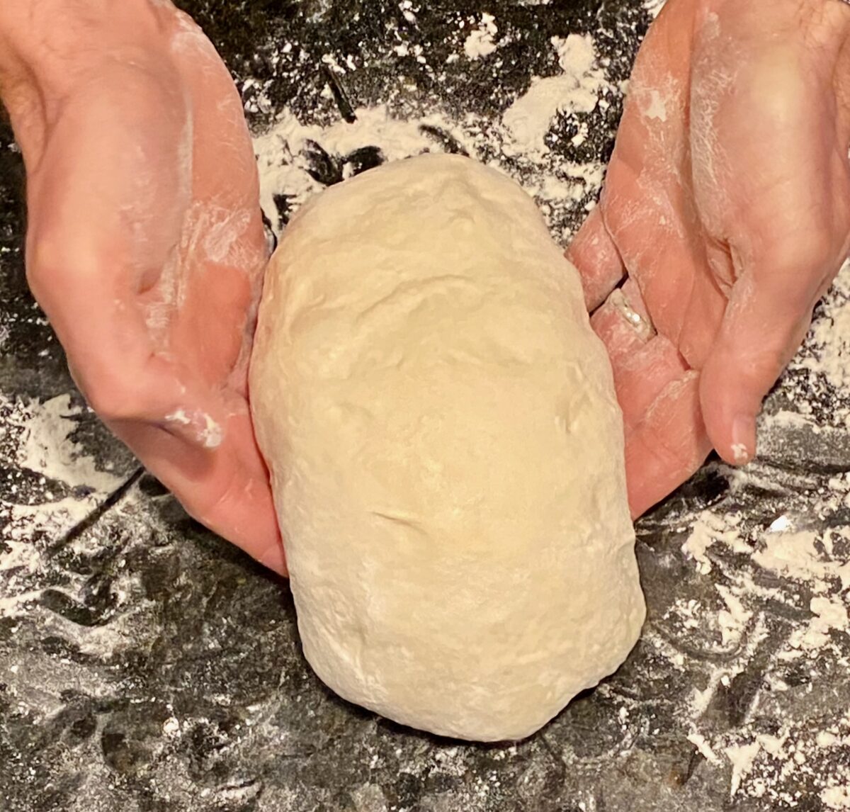 Here, we're trying to shape and tighten the dough ball. We're gently pressing the dough in and down, which stretches the dough across the top. 