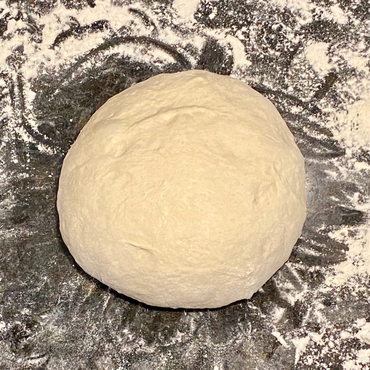 The dough ball after shaping and tucking. The ball is round and smooth on top.