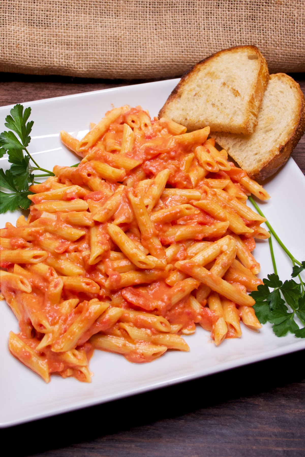 Pasta alla vodka on a serving platter with Italian parsley and rustic bread.