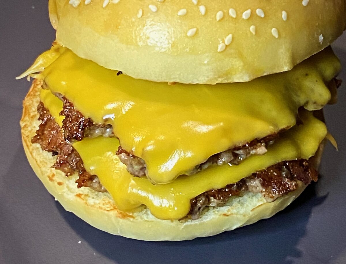Double smash burger with cheese on sesame seed bun.