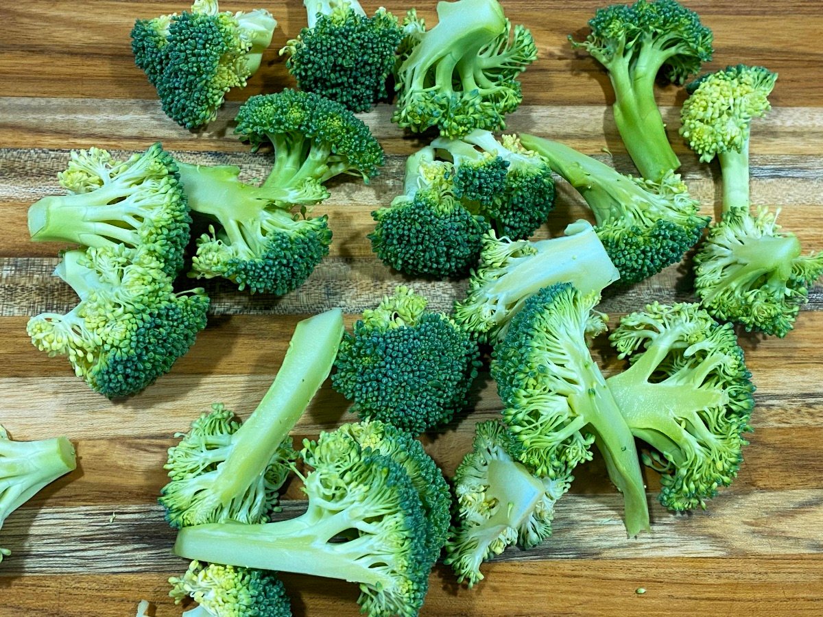 Brocolli florettes on wooden cutting board.